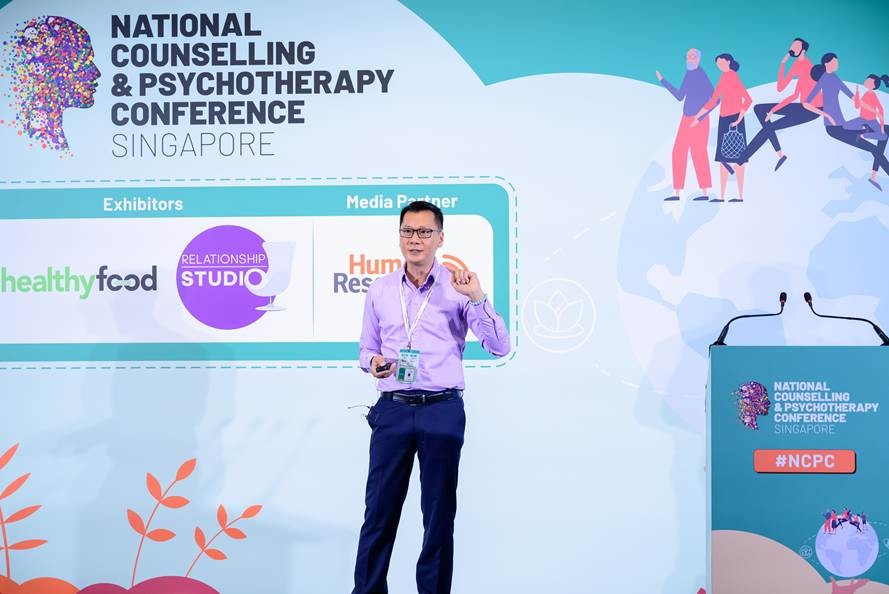 Krish Phua presenting on stage at the National Counselling & Psychotherapy Conference Singapore