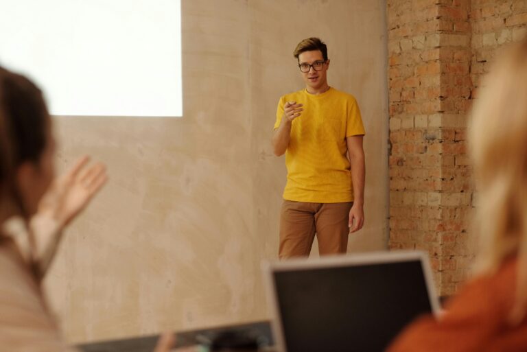 man in yellow tshirt and brown pants holding a speech and answering questions from the audience