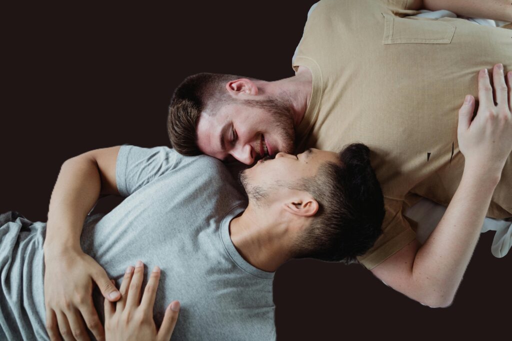 mixed male couple on bed smiling at each other