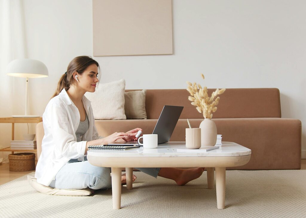 woman in her living room sitting on the floor typing something into a laptop