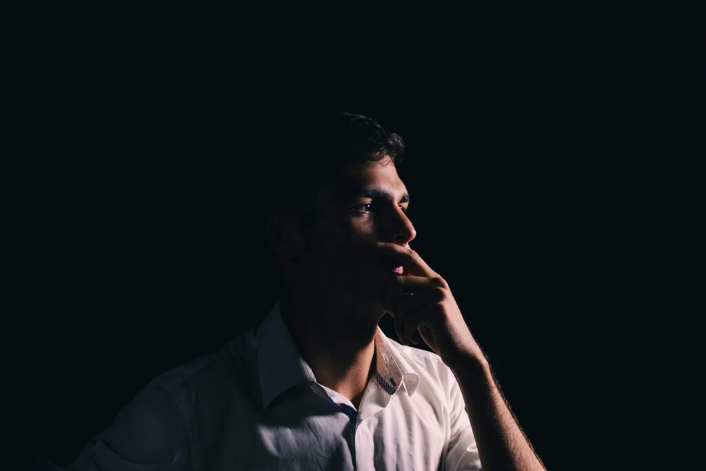 Portrait of a man looking to the side and his hand covering his mouth symbolising anxiety.