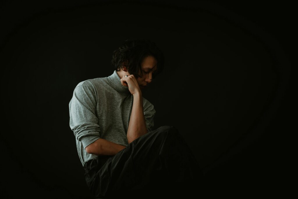 man from the side supporting his head with his arm and looking down symbolising confusion and self-doubt