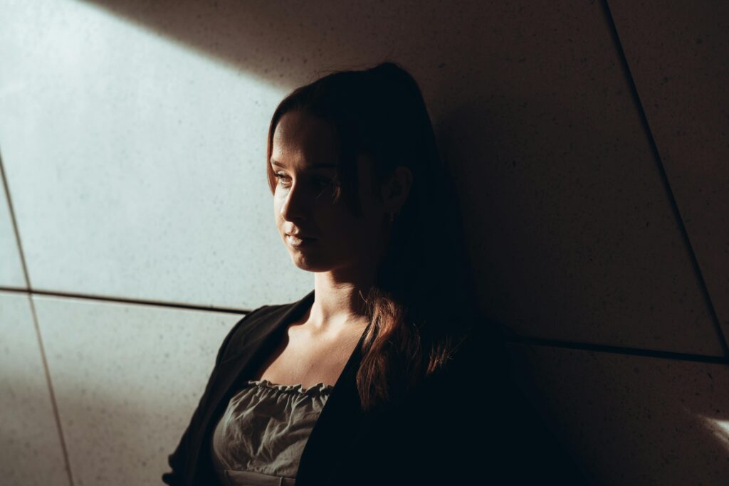 woman leaning against wall in the dark symbolising conflicts at work