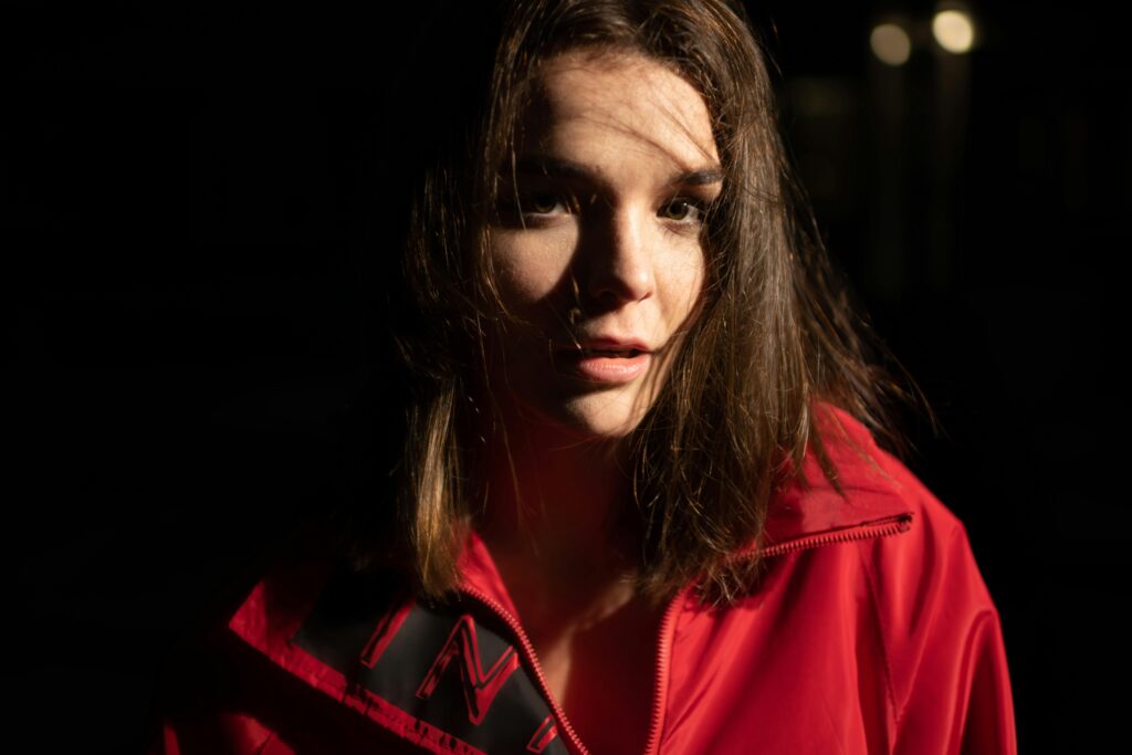 young woman in red jacket and wild hair and a shocked look upon her face symbolising being overwhelmed and burn out