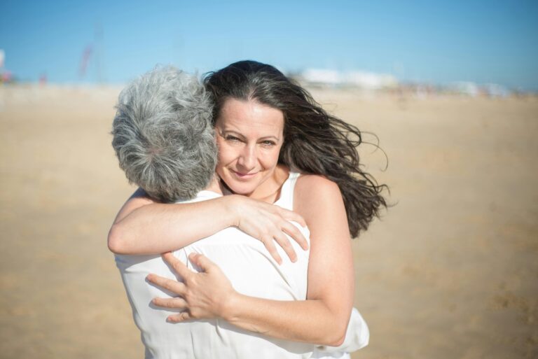 A heartfelt embrace between a mother and daughter on a sunny beach in Portugal.